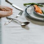 A child's hands at a dining table with plates of vegetables, showcasing a healthy meal.